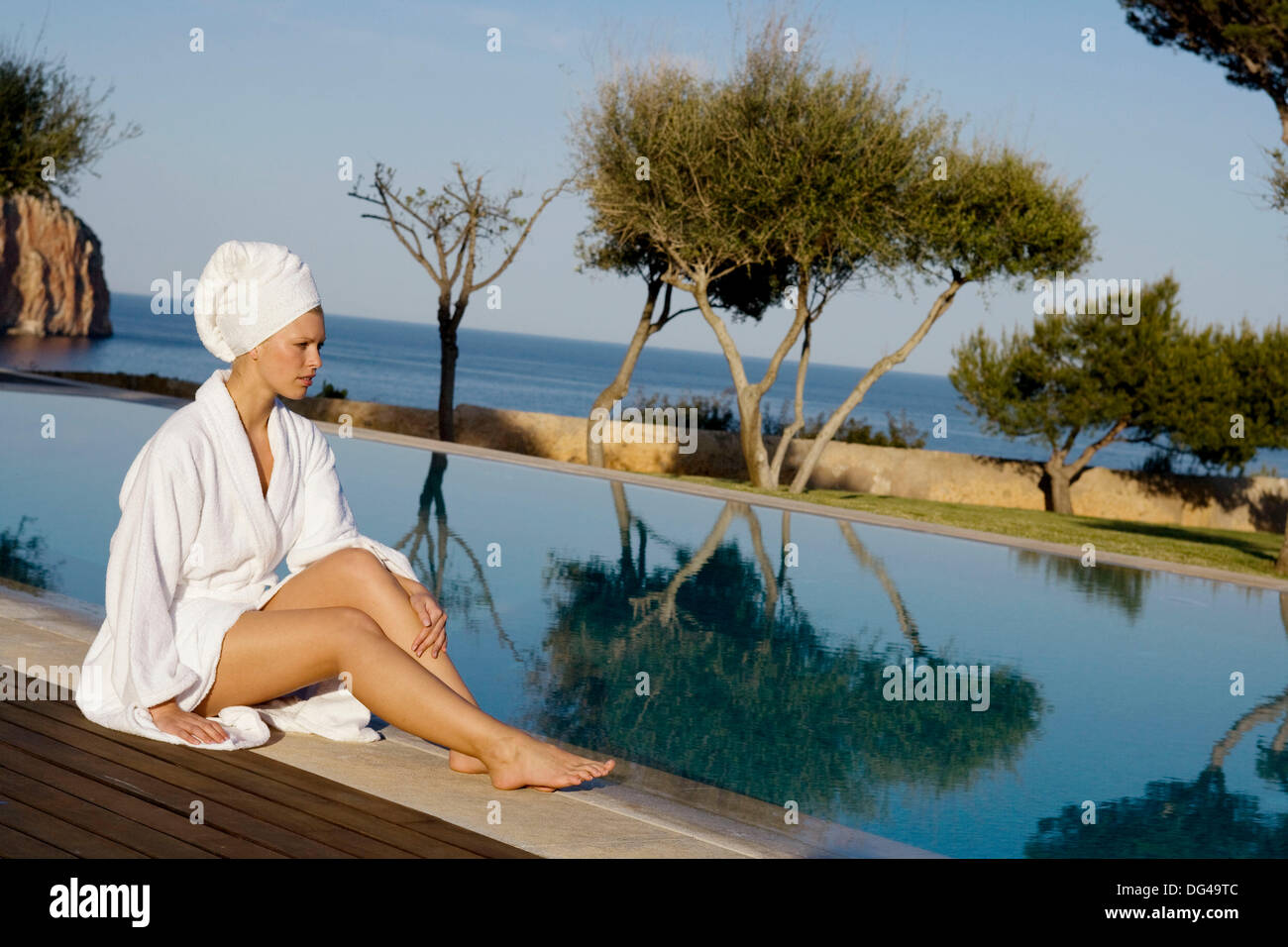 Woman in bathrobe sitting by the swimming pool Stock Photo Alamy
