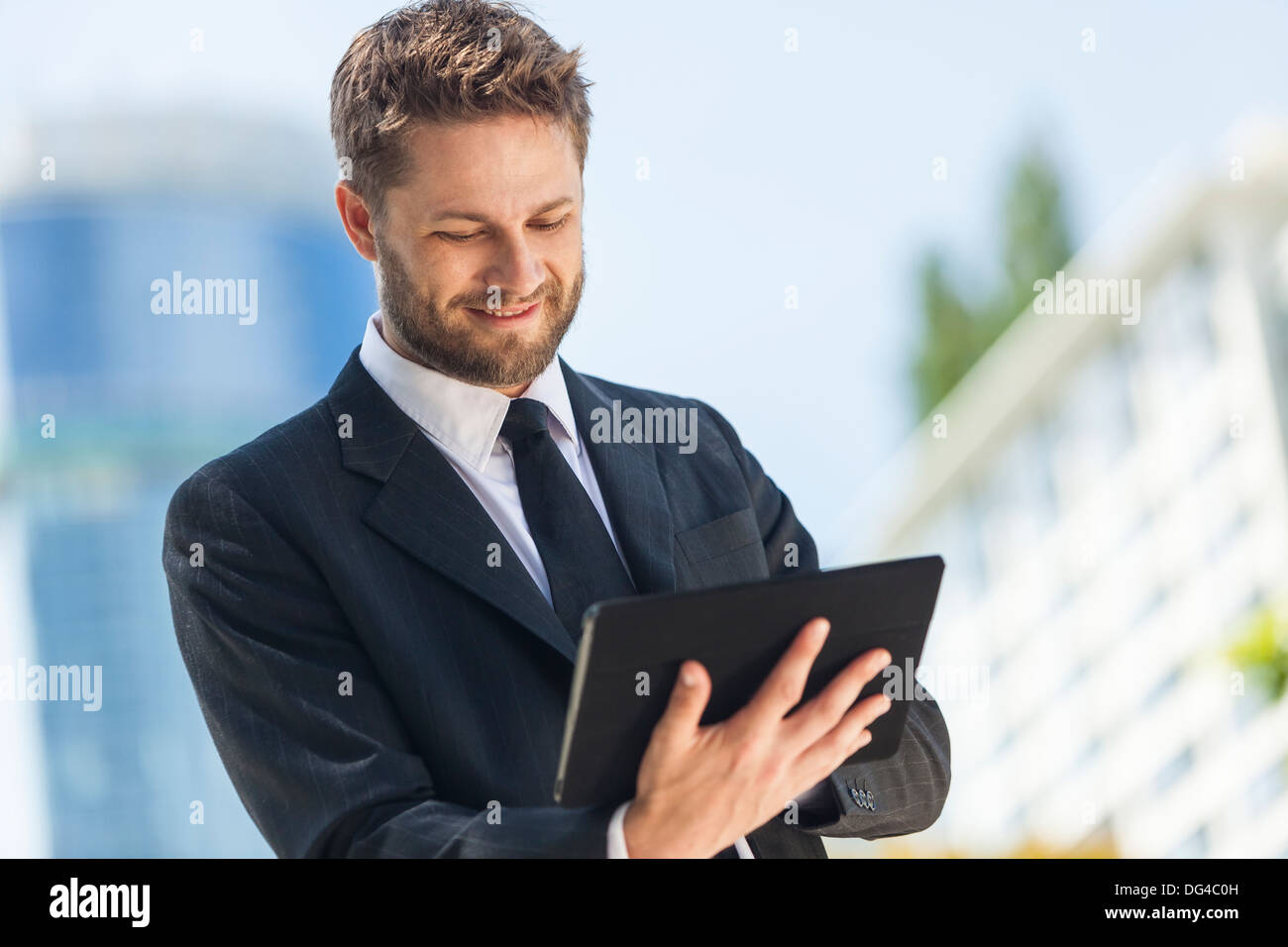 A smart young businessman with a beard using a tablet computer Stock Photo