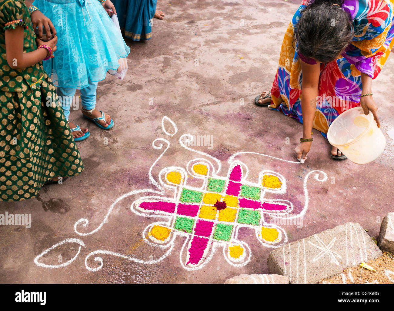 Indian woman making Dasara Rangoli festival coloured powder design. Puttaparthi, Andhra Pradesh, India Stock Photo