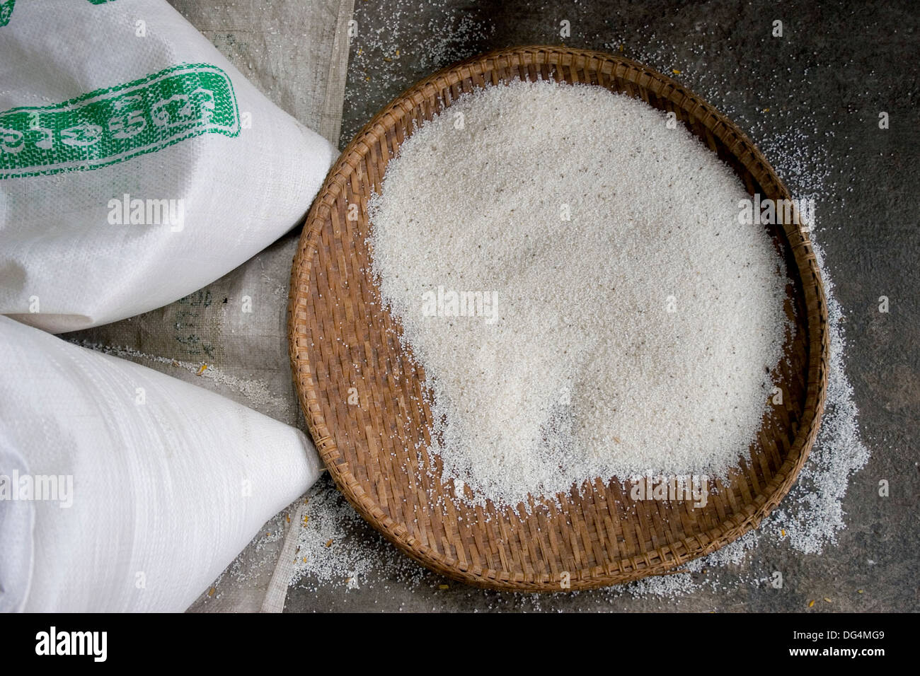 A basket filled with milled rice sits near rice bags at a rice store in Phnom Penh, Cambodia. Stock Photo