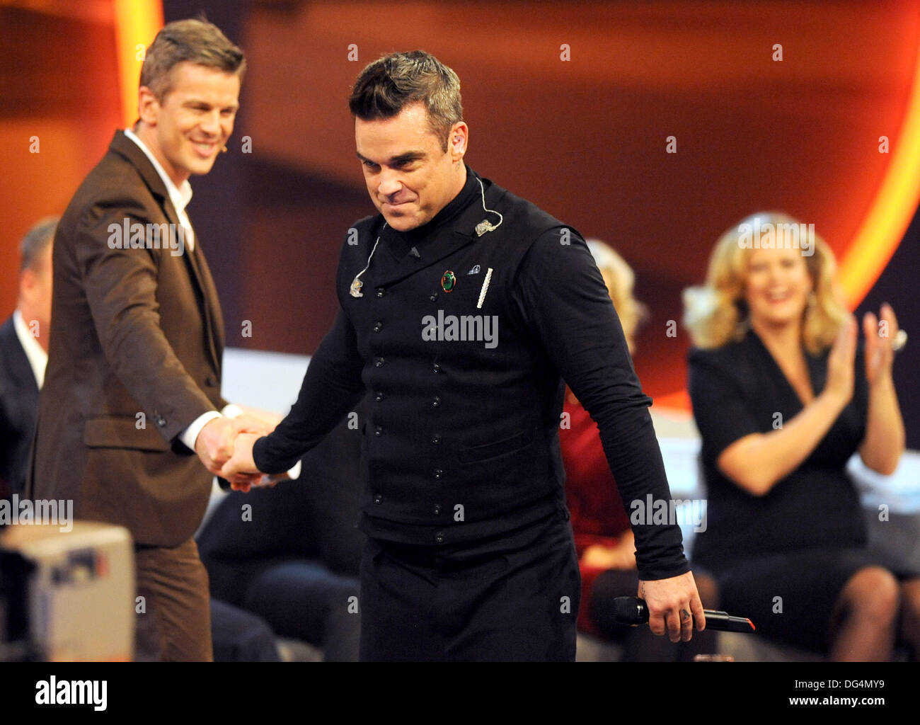 German actress Barbara Schoeneberger (L) and German television host Markus Lanz (R) talk to British singer Robbie Williams (C) during the German television game show 'Wetten Das.? (Wanna bet.?), hosted by Markus Lanz (L) at the OVB-Arena in Bremen, Germany 3 November 2012. Photo: Ingo Wagner Stock Photo