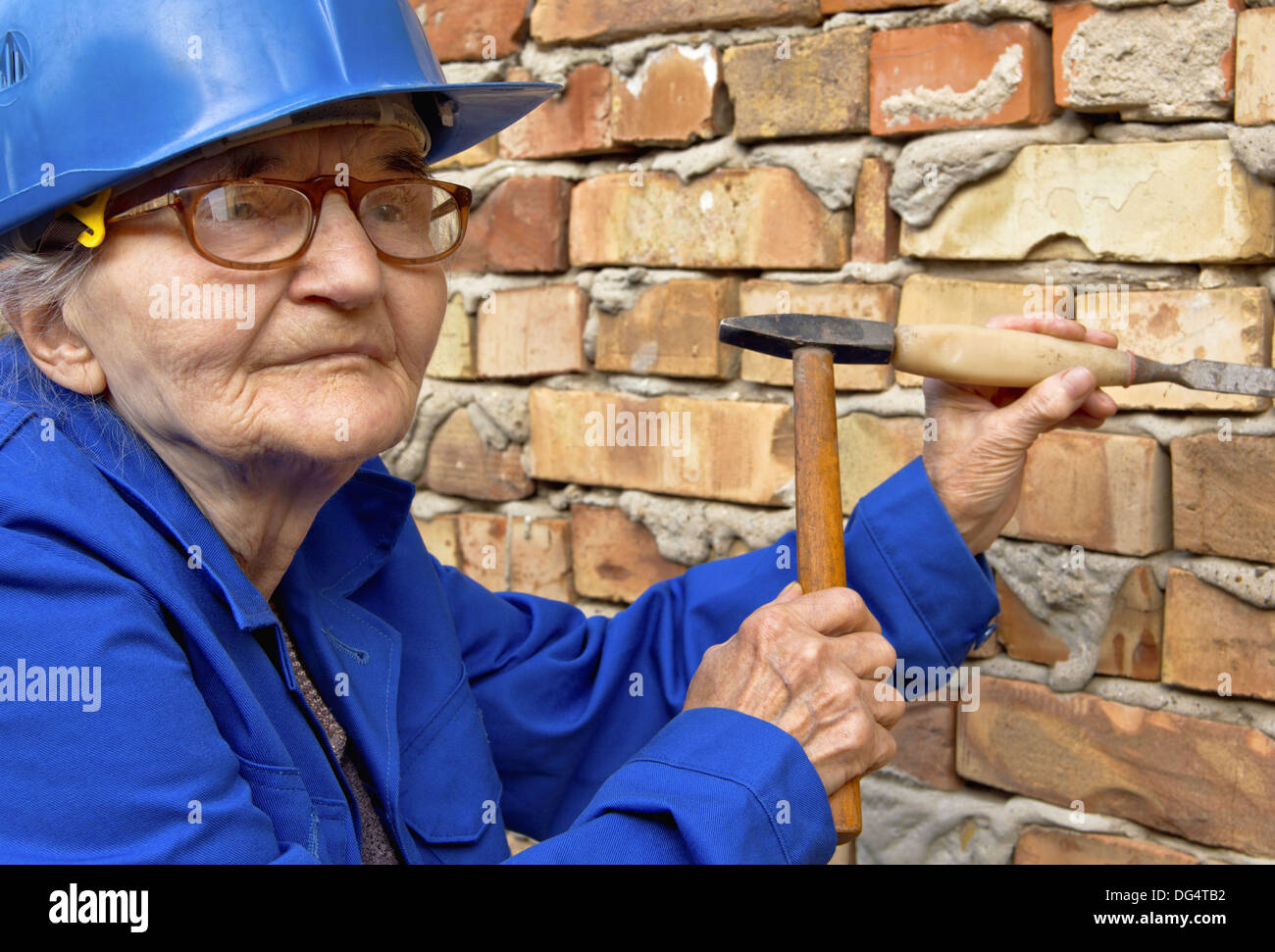 Elderly woman holding a hammer and chisel. Construction background Stock Photo