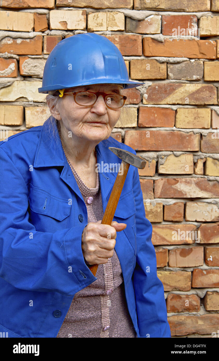 Elderly woman holding a hammer. Construction background. Stock Photo