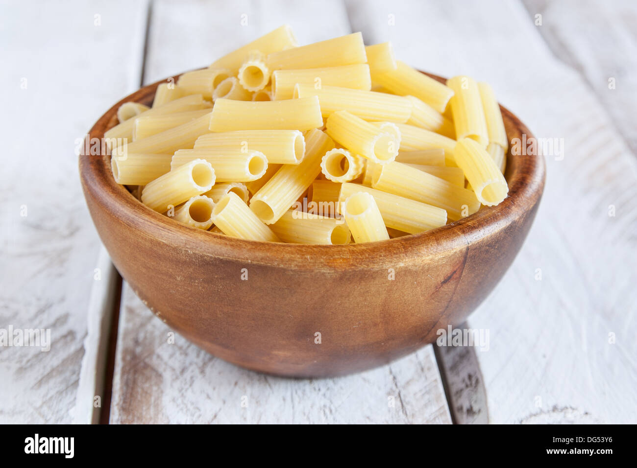 Uncooked rigatoni bowl on wooden table Stock Photo