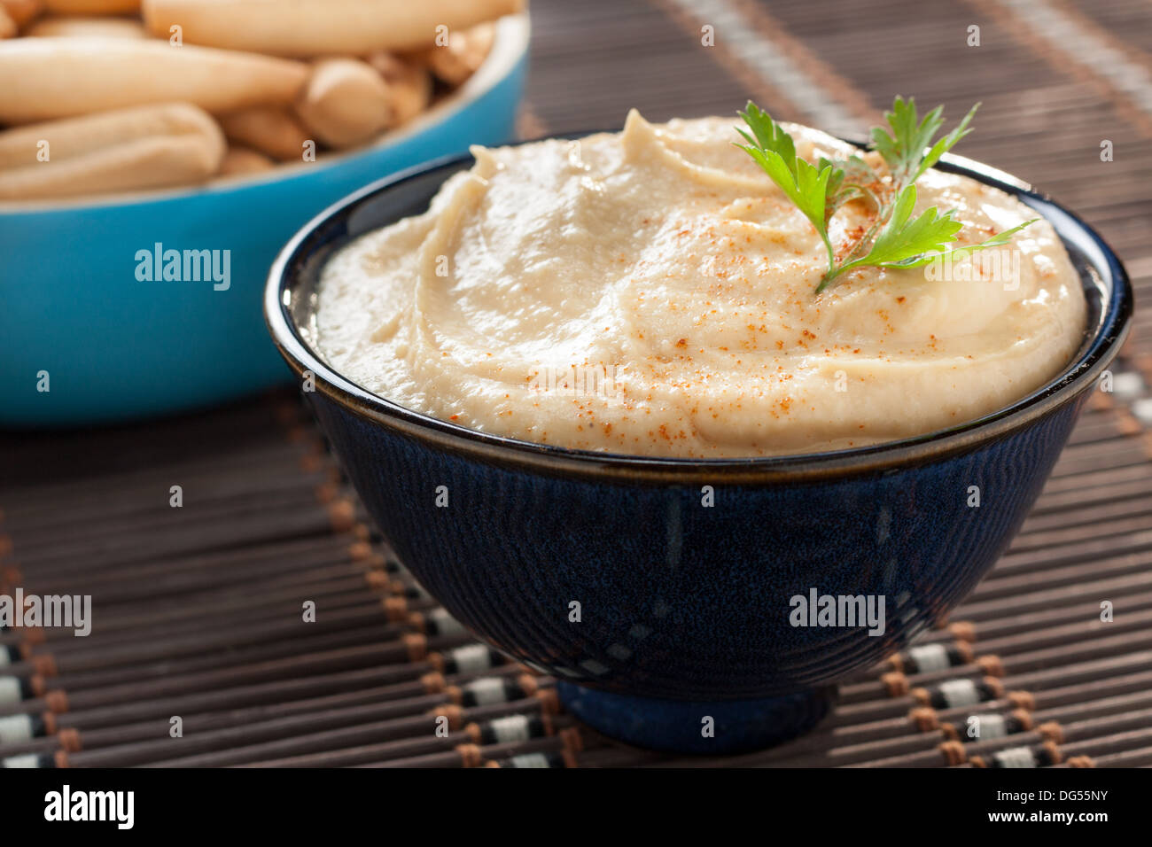 bowl of hummus with parsley and bread sticks Stock Photo