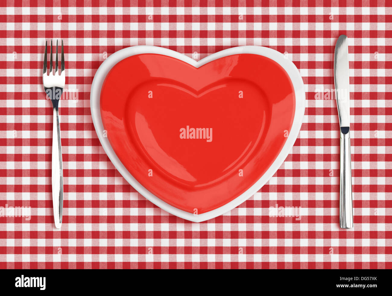 Knife, heart plate and fork on checked tablecloth Stock Photo