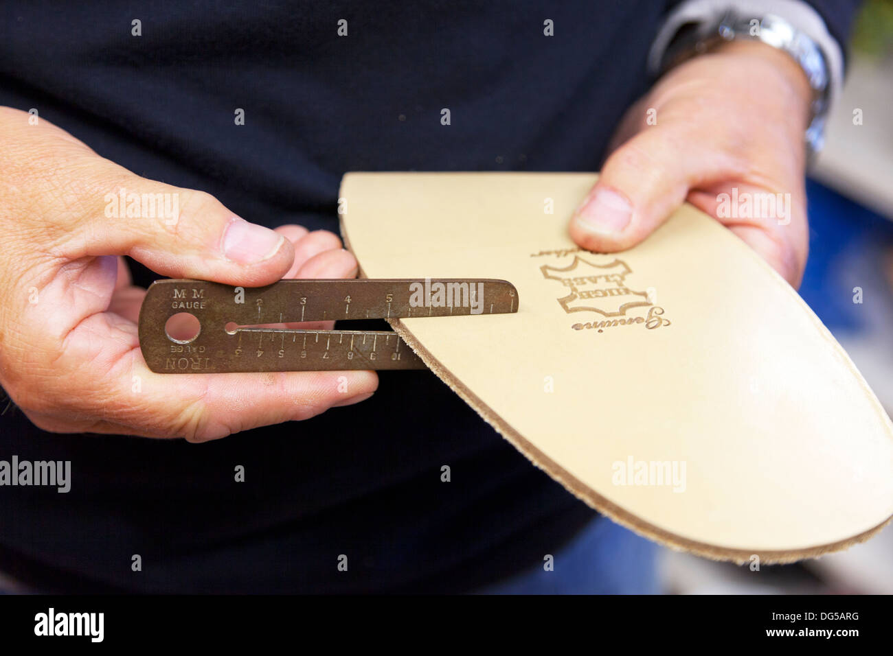 Male mans hands using iron measurer to measure thickness of leather