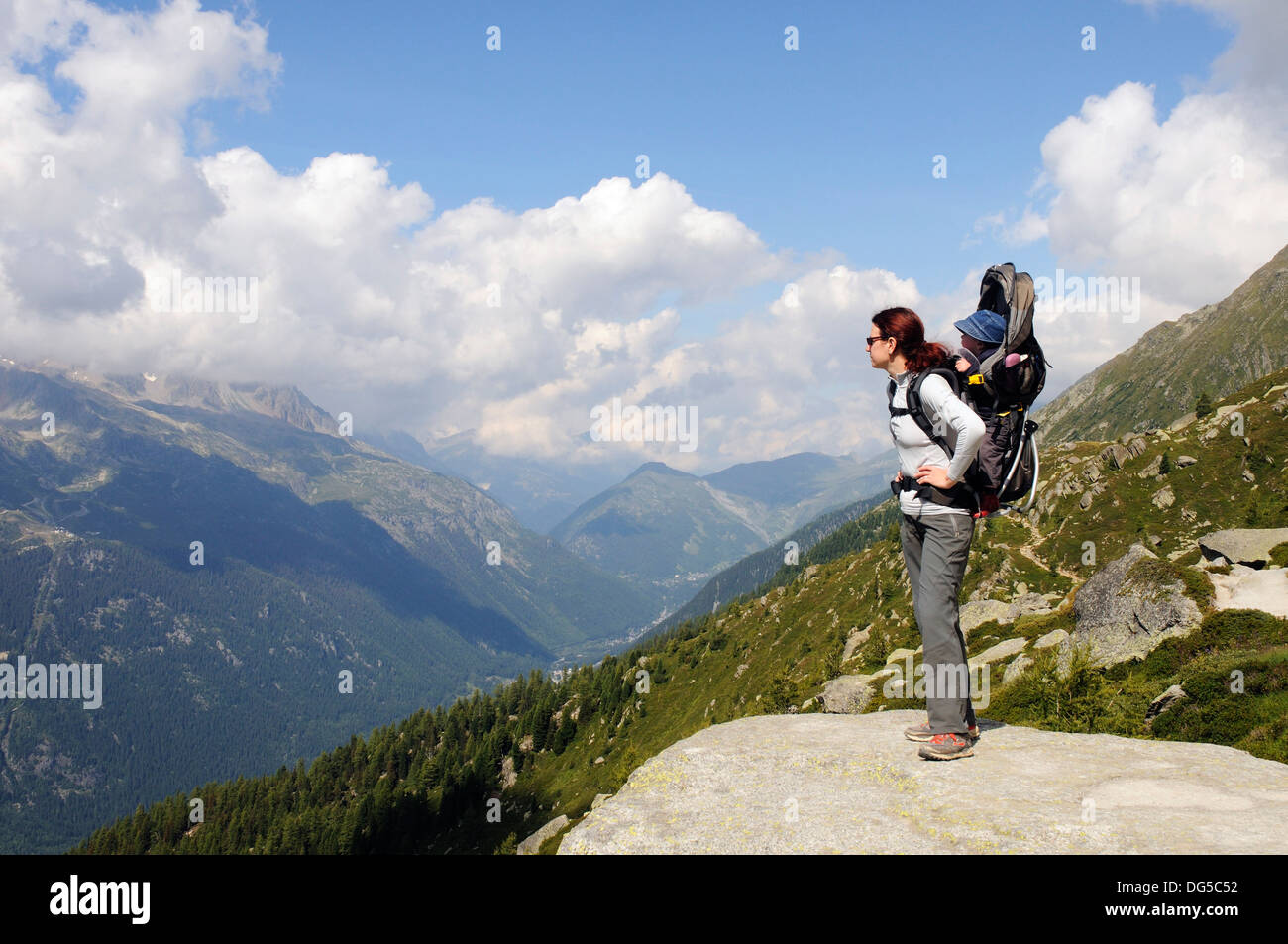 A mother hiking in the French alps carrying her child in a baby carrier Stock Photo