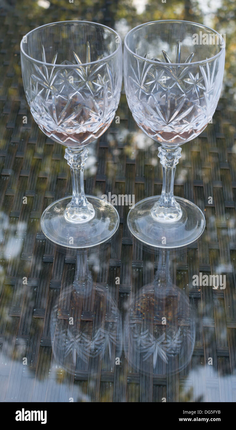 Rose wine in two glasses on a glass table outdoors with reflection from trees. Stock Photo