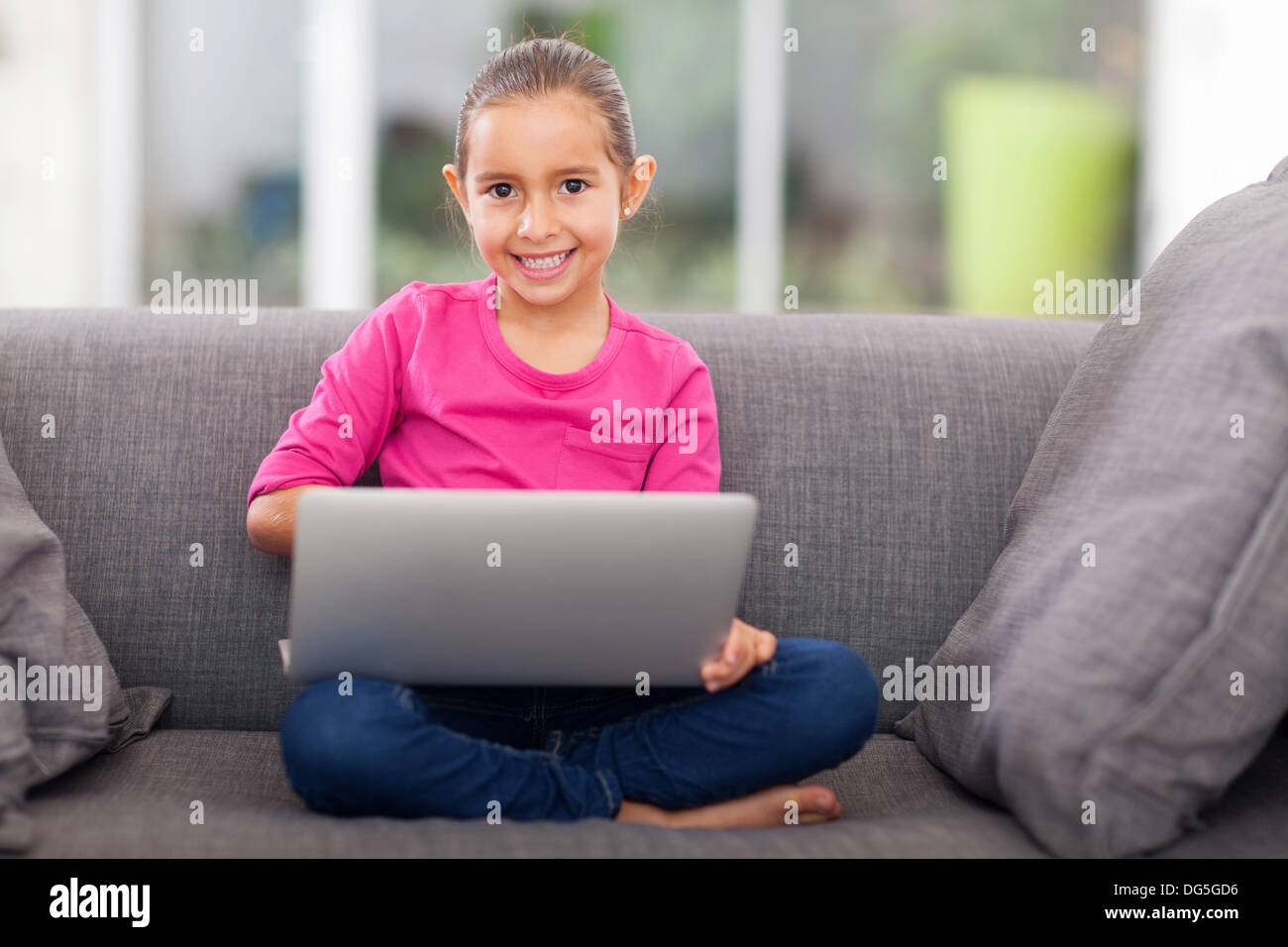 pretty little girl using laptop on sofa at home Stock Photo - Alamy