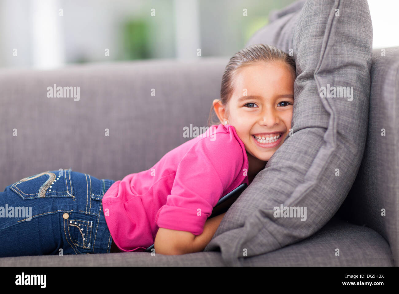 beautiful little girl lying on a couch with a tablet pc Stock Photo - Alamy