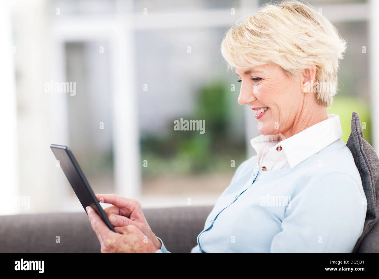 pretty senior woman using tablet computer at home Stock Photo