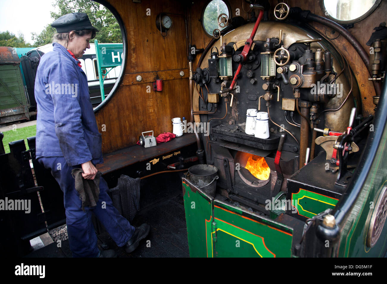 A female engine driver working the footplate of a steam locomotive on the heritage Bluebell railway line. Stock Photo