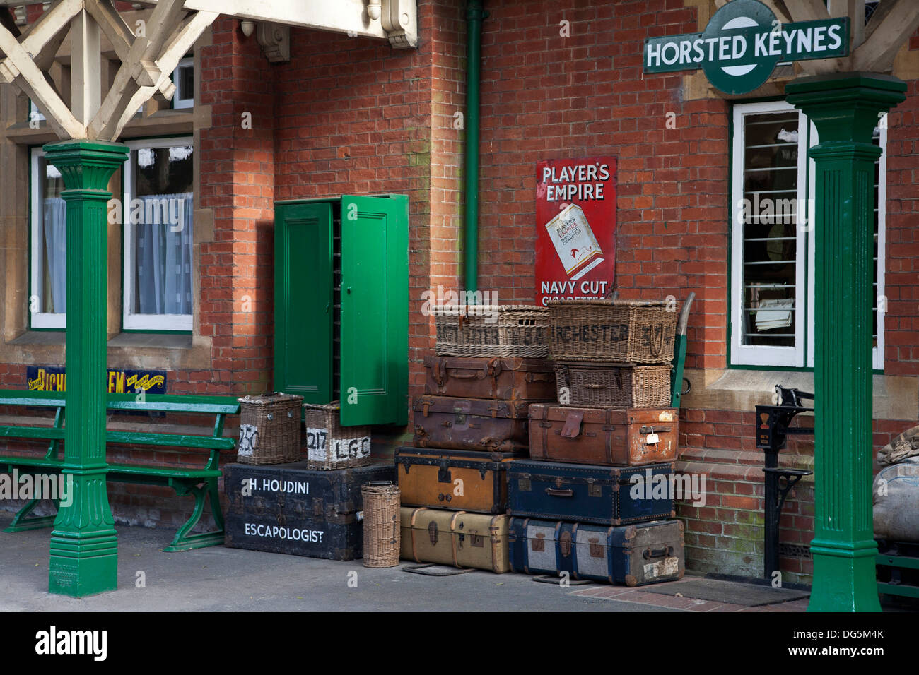 Vintage suitcases stacked against the wall of Horsted Keynes railway platform. H. Houdini escapologist case also. Stock Photo