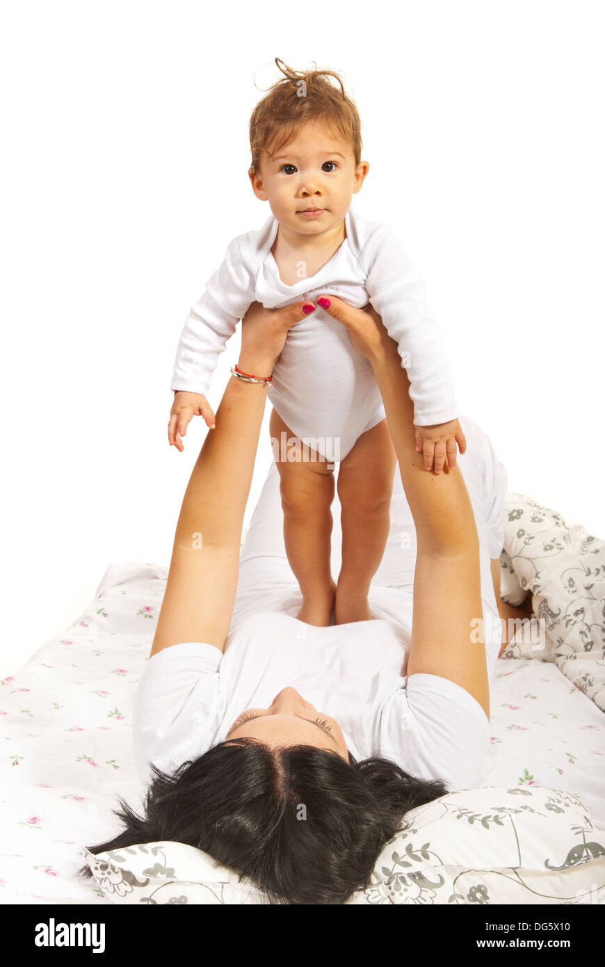 Boy standing on mommys stomach in their bed Stock Photo