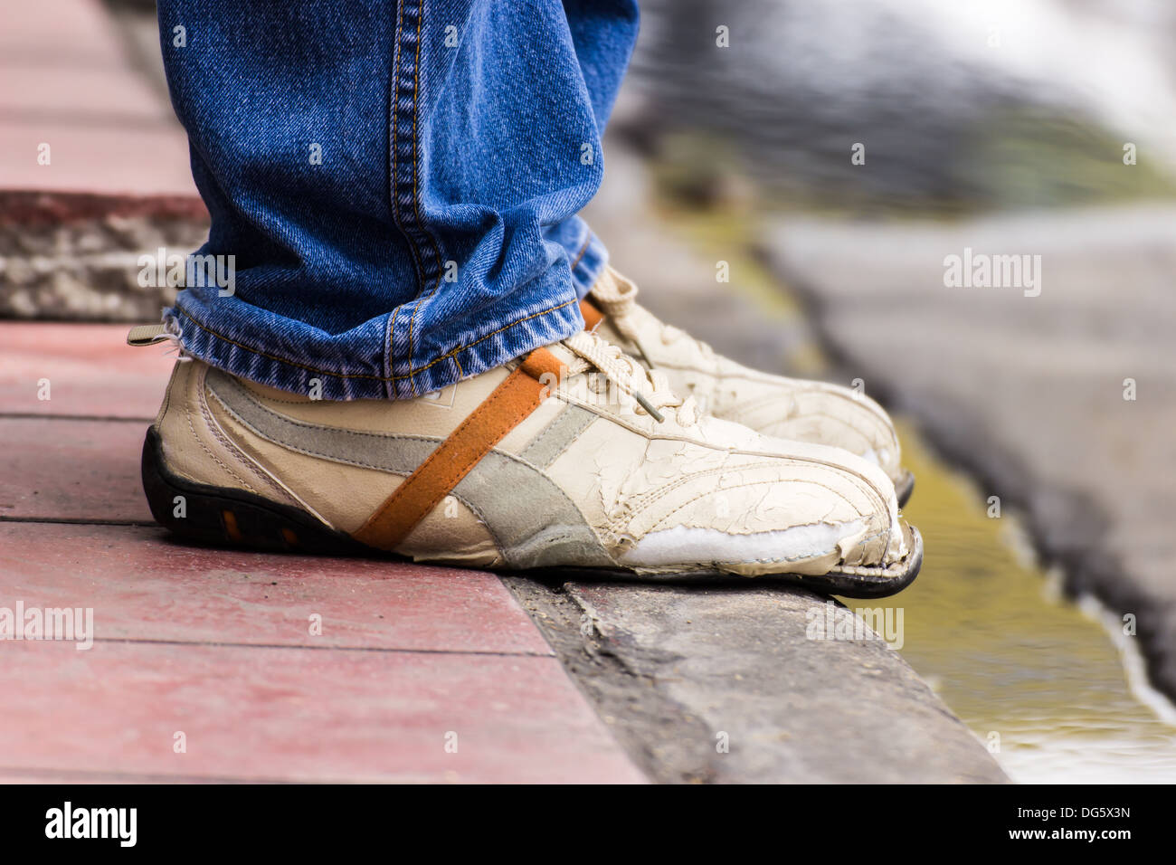 Ripped shoes, waiting someone at a bus stop in Bangkok, Thailand Stock Photo