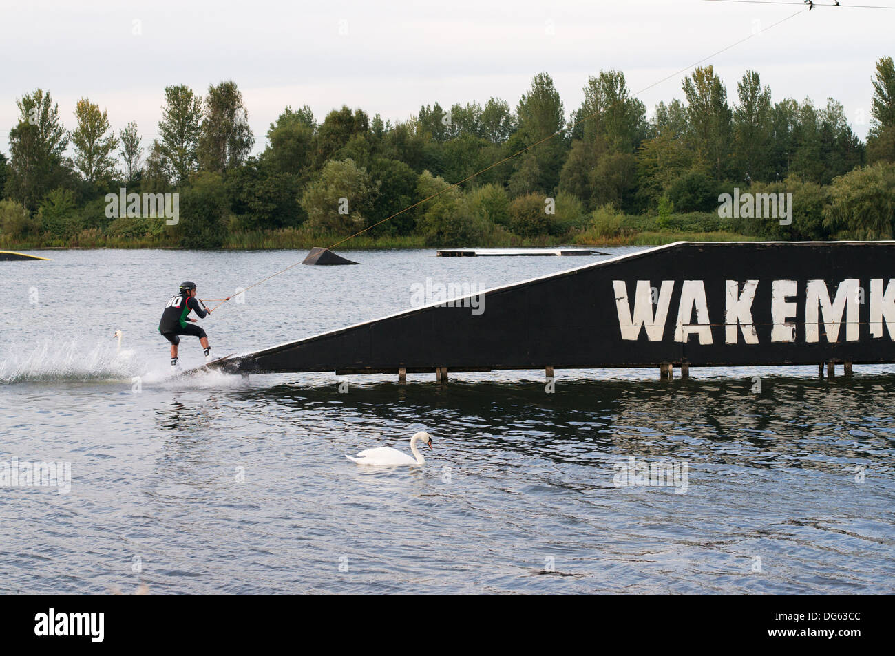 A wakeboarder about to ascend a ramp at the WAKEMK cable wakeboard and waterski centre Milton Keynes, England UK Stock Photo