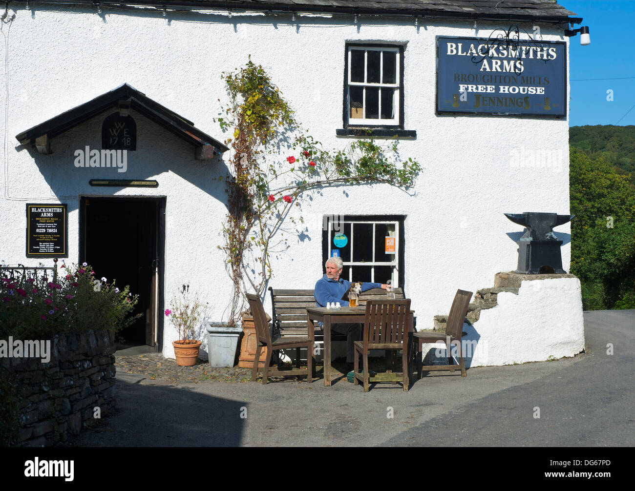 Man and dog outside the Blacksmiths Arms, Broughton Mills, Lake