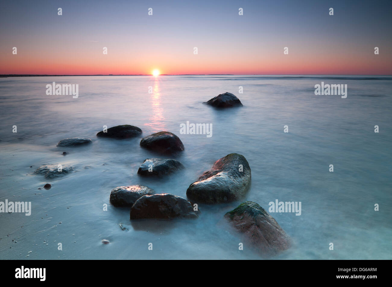 Sunset scenic view over Baltic Sea with stones in foreground. Long exposure. Stock Photo