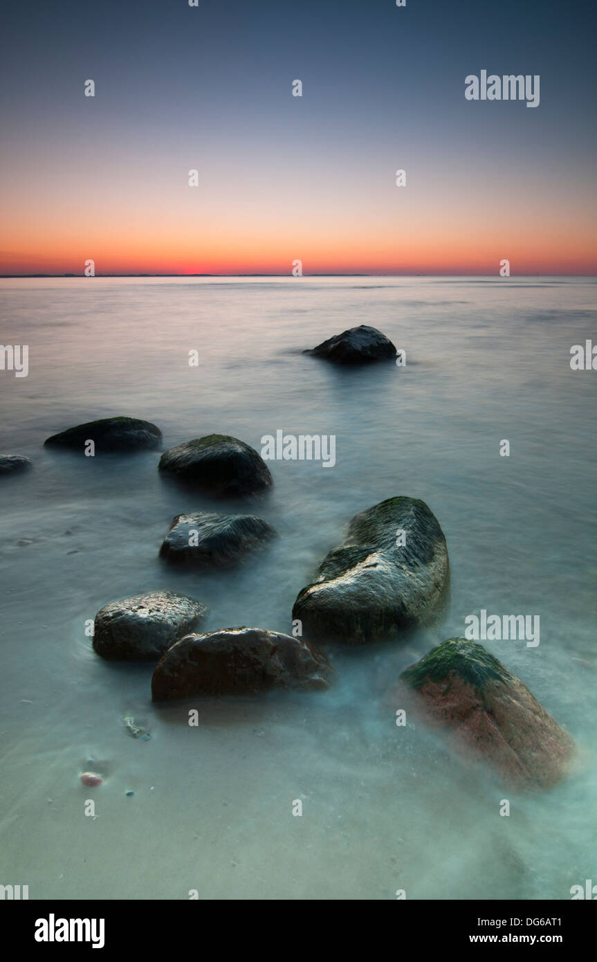Sunset scenic view over Baltic Sea with stones in foreground. Long exposure. Stock Photo