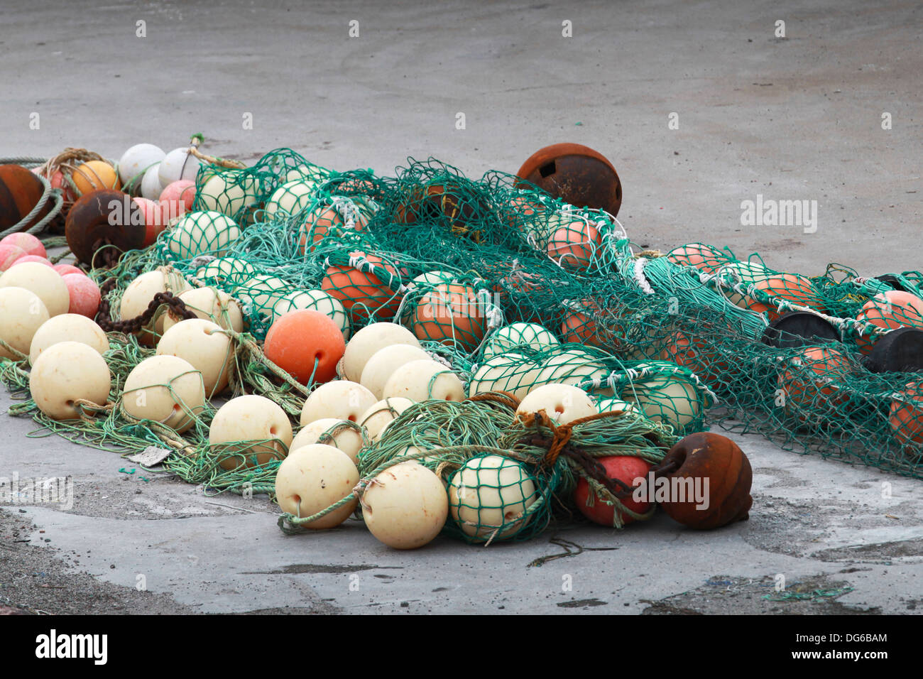 Green fishing net with spherical buoys lay on the coast Stock Photo