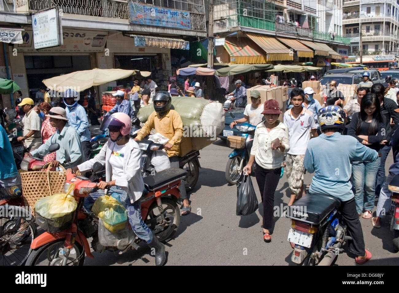 Several cyclo drivers are peddling along with motorcycle drivers on a busy street in Phnom Penh, Cambodia. Stock Photo