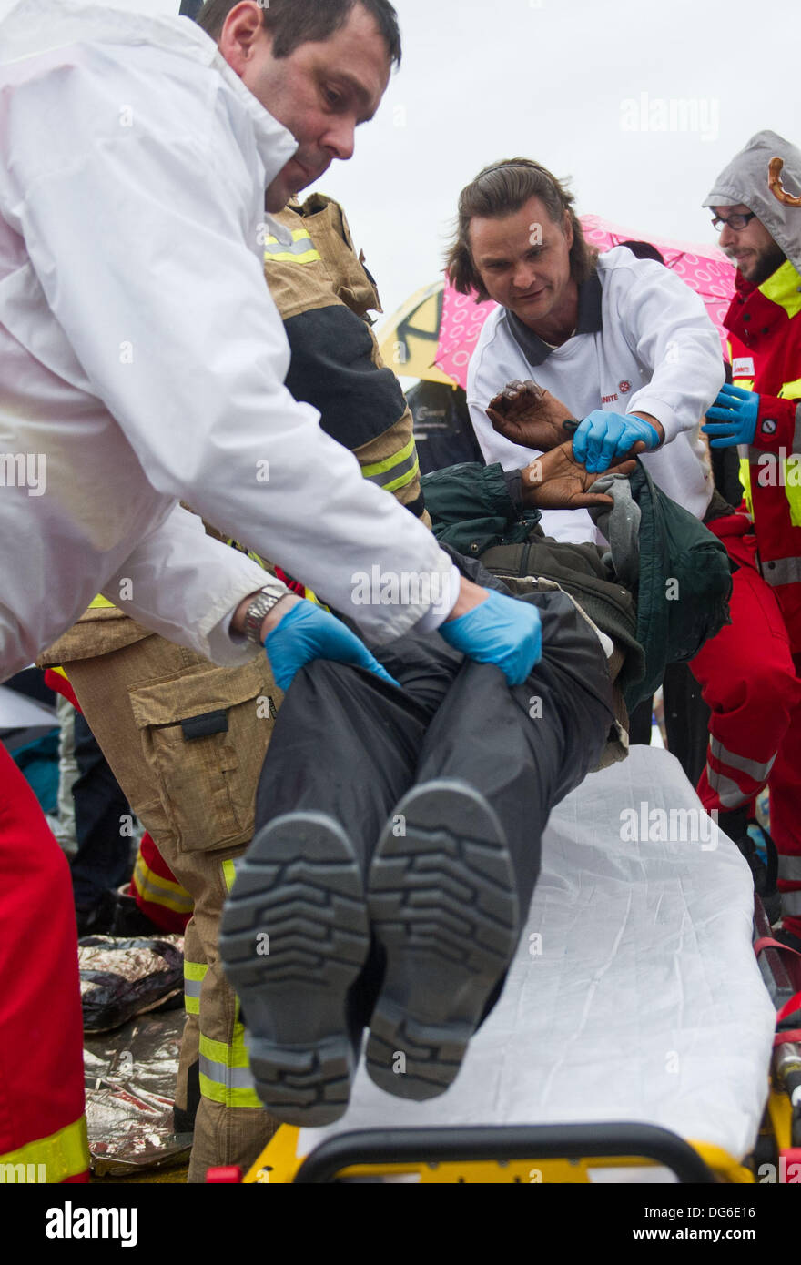 Berlin, Germany. 15th Oct, 2013. A refugee is put on a stretcher by rescue workers at square Pariser Platz in Berlin, Germany, 15 October 2013. Three refugees had to be taken to the hospital because of their poor state of health. The refugees have been on hunger strike since 09 October 2013. Photo: OLE SPATA/dpa/Alamy Live News Stock Photo