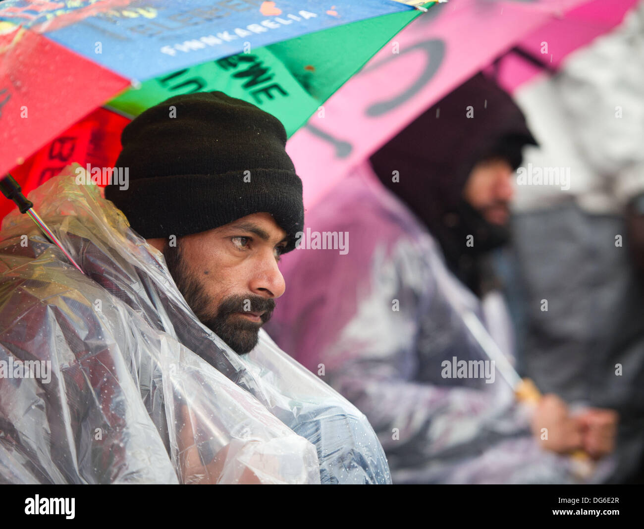 Berlin, Germany. 15th Oct, 2013. Refugee sit under umbrellas on Pariser Platz in Berlin, Germany, 15 October 2013. Three refugees had to be taken to hospital because of their poor state of health. The refugees have been on hunger strike since 09 October 2013. Photo: OLE SPATA/dpa/Alamy Live News Stock Photo