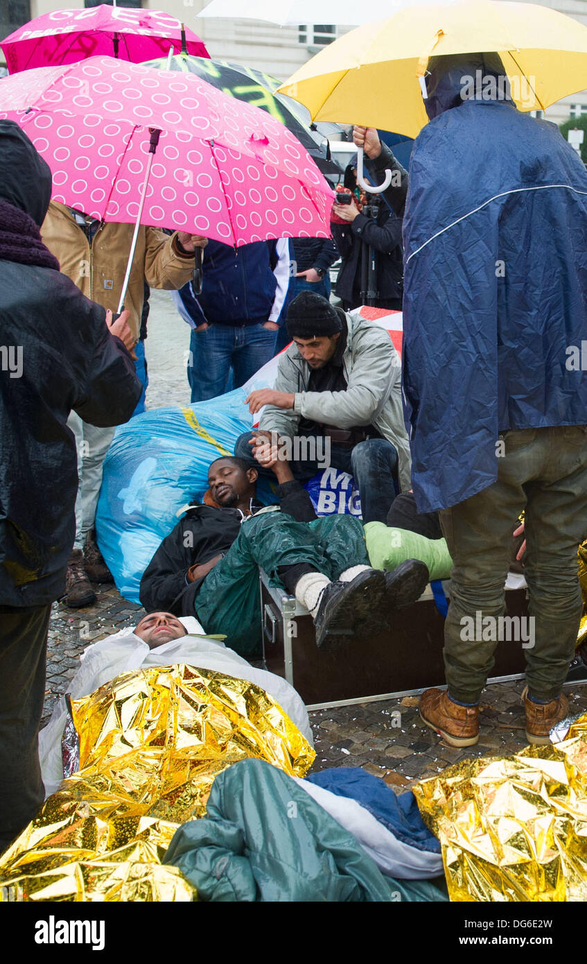 Berlin, Germany. 15th Oct, 2013. Two refugees lie exhausted on Pariser Platz as rescue workers plan their transport to a hospital in Berlin, Germany, 15 October 2013. Three refugees had to be taken to hospital because of their poor state of health. The refugees have been on hunger strike since 09 October 2013. Photo: OLE SPATA/dpa/Alamy Live News Stock Photo