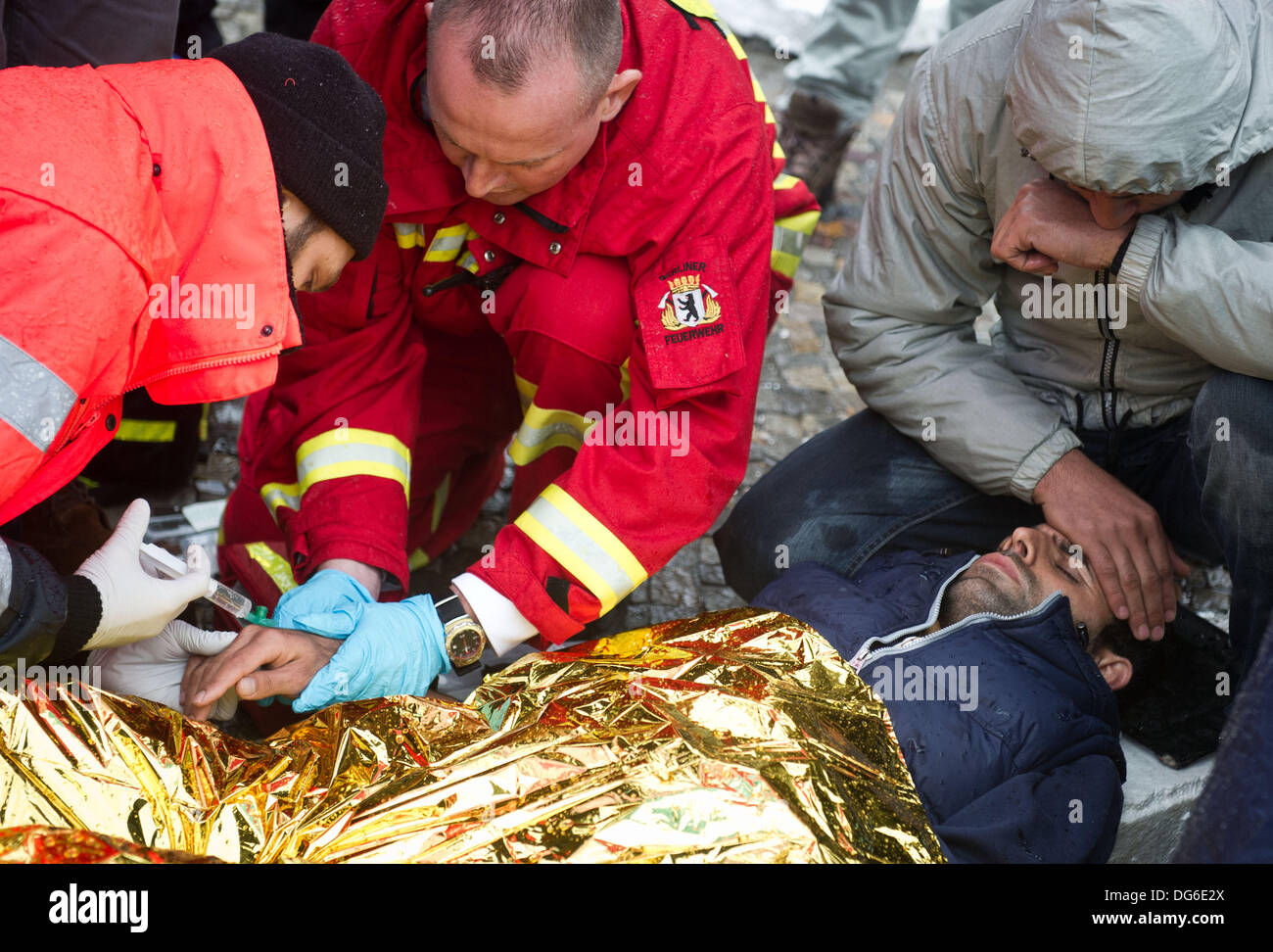 Berlin, Germany. 15th Oct, 2013. Rescue workers treat a refugee on Pariser Platz in Berlin, Germany, 15 October 2013. Three refugees had to be taken to hospital because of their poor state of health. The refugees have been on hunger strike since 09 October 2013. Photo: OLE SPATA/dpa/Alamy Live News Stock Photo