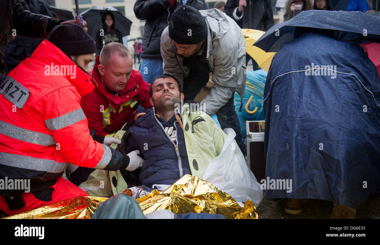Berlin, Germany. 15th Oct, 2013. A refugee lies under space blankets and is taken care of by rescue workers on Pariser Platz in Berlin, Germany, 15 October 2013. Three refugees had to be taken to hospital because of their poor state of health. The refugees have been on hunger strike since 09 October 2013. Photo: OLE SPATA/dpa/Alamy Live News Stock Photo