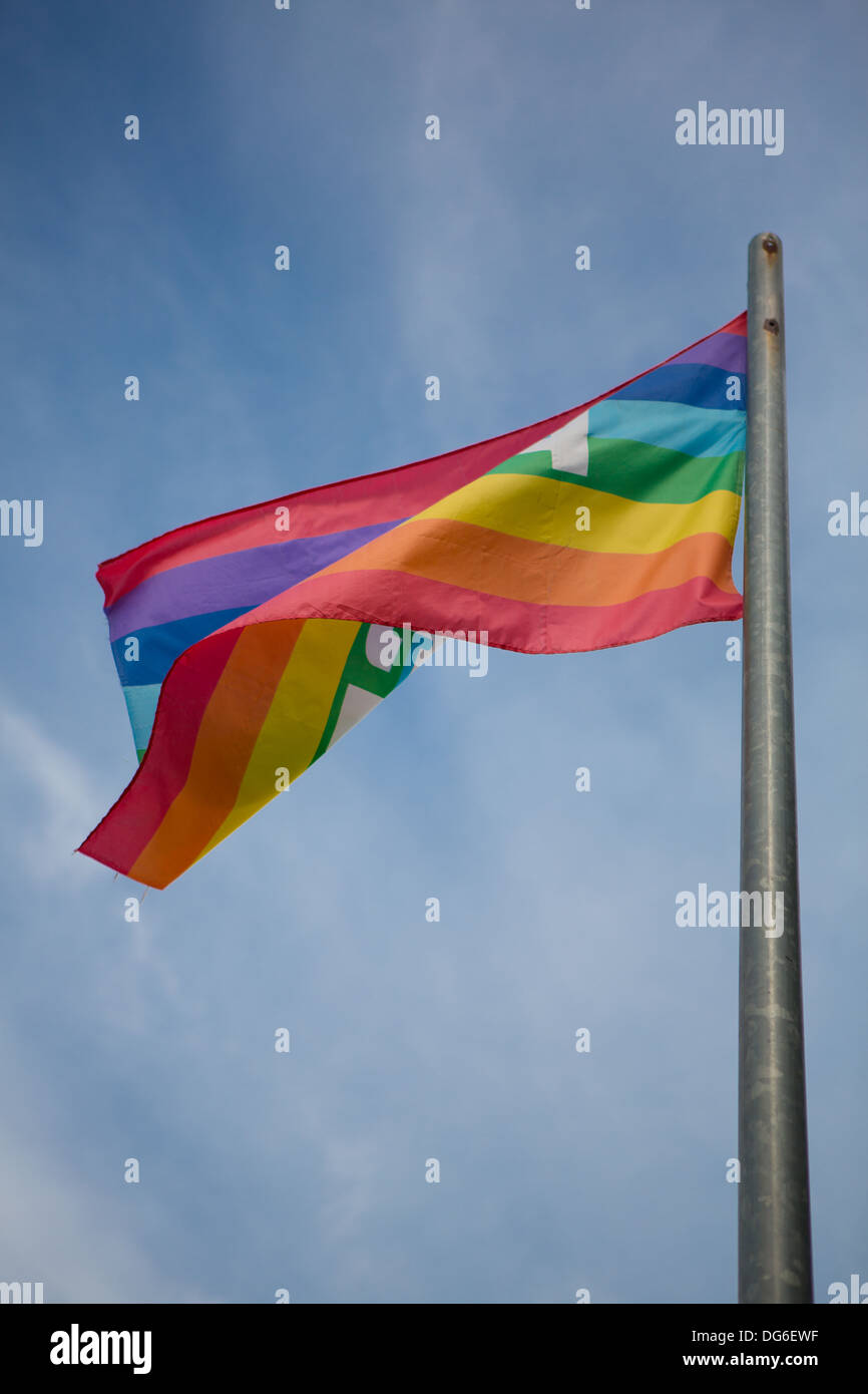 flag in rainbow colors flying against a clear blue sky in sunny weather Stock Photo