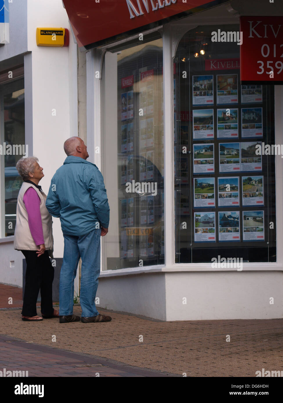 Old couple looking in estate agent's window, Bude, Cornwall, UK Stock