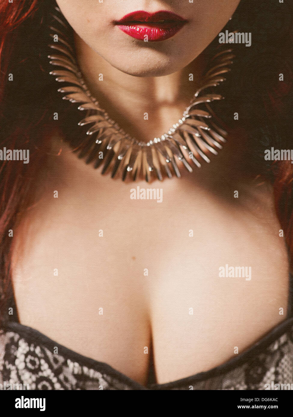Lady with red hair, cherry red lips, spiky jewellery and exposed cleavage. Stock Photo