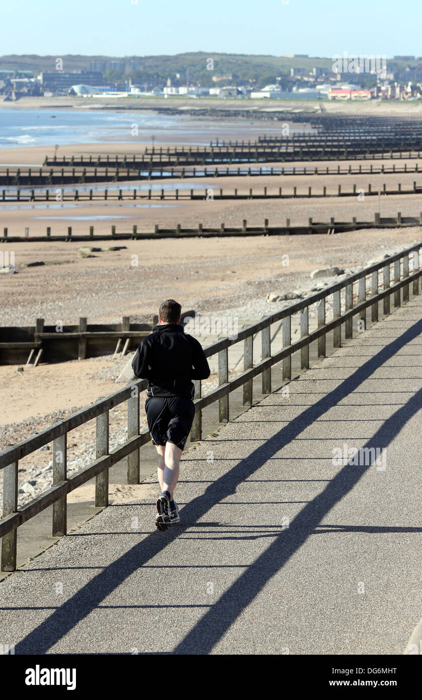 Rear view of Jogger running on Aberdeen beach, Scotland, UK Stock Photo