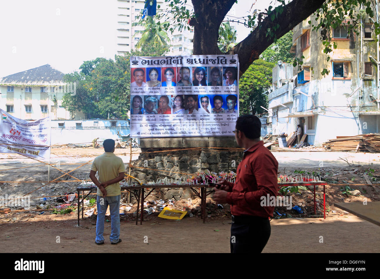 Mumbai, Maharashtra, India. 3rd Oct, 2013. A passerby reads a placard paying homage to those killed in the recent building Collapse on 27th Sept. at Dockyard road killing 61 people. There has been a series of deadly building collapses in Mumbai in 2013 that have brought into sharp focus the city's problems with dangerous and illegal buildings that often house the poor. Mumbai, the financial capital of India, with an ever-growing population that is currently more than 15 million, has a severe shortage of land and property prices are sky-high, forcing many residents into unsafe buildings. Se Stock Photo