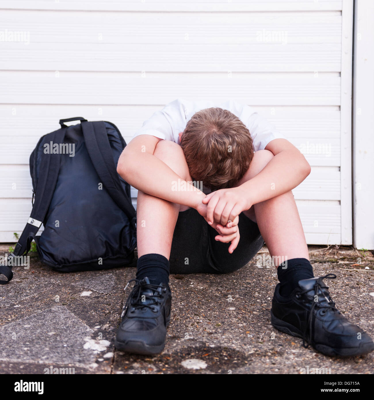 A boy of 10 looking sad and depressed in his school uniform showing the effects of bullying in the Uk Stock Photo