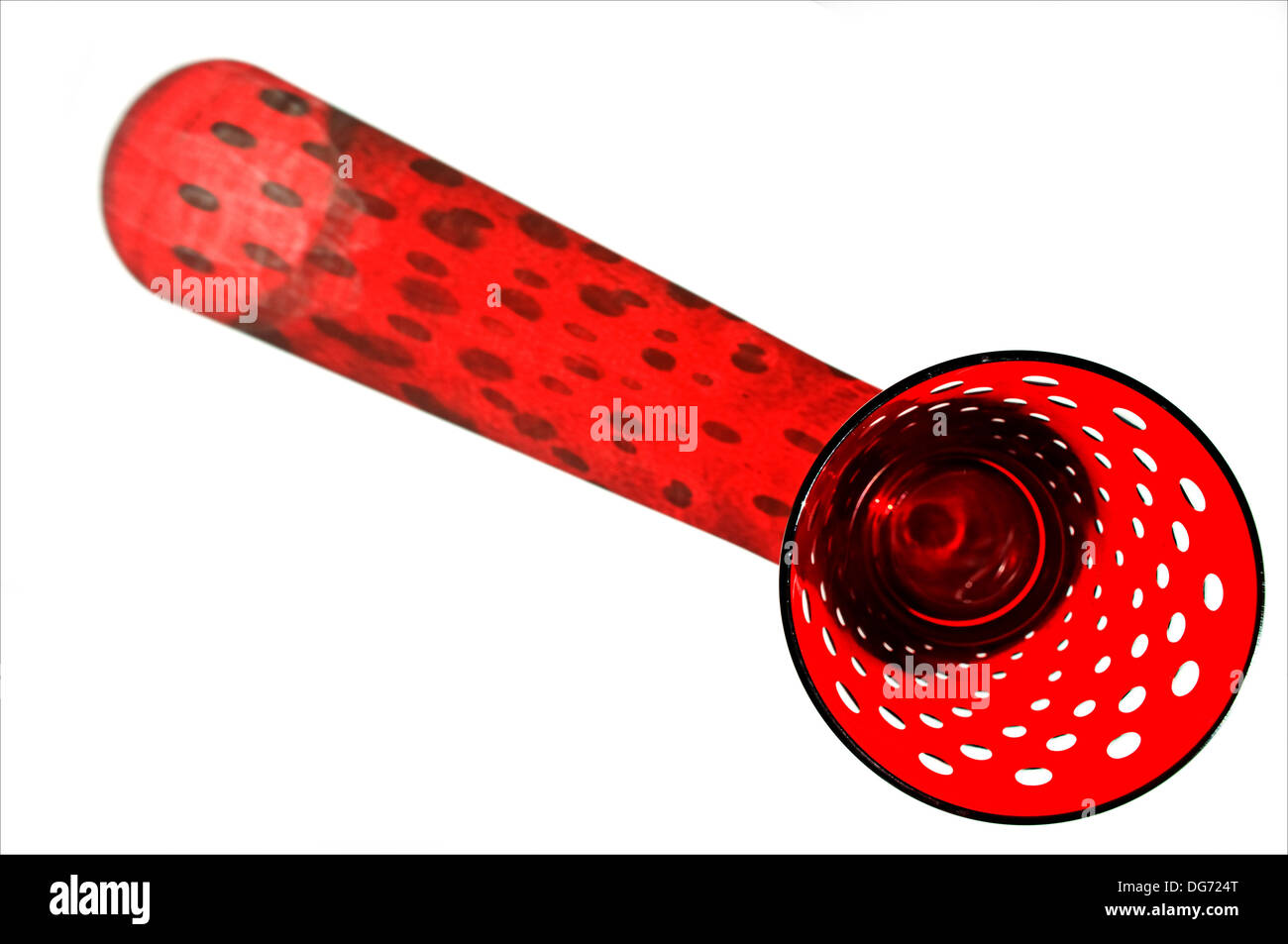 Spotted red glass tumbler, with a red shadow, cast by natural light, on a white background. Stock Photo