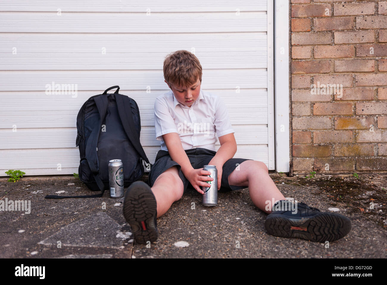 A boy of 10 in his school uniform drinking lager alcohol showing the