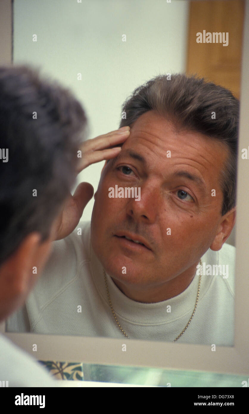 middle aged man looking in mirror Stock Photo