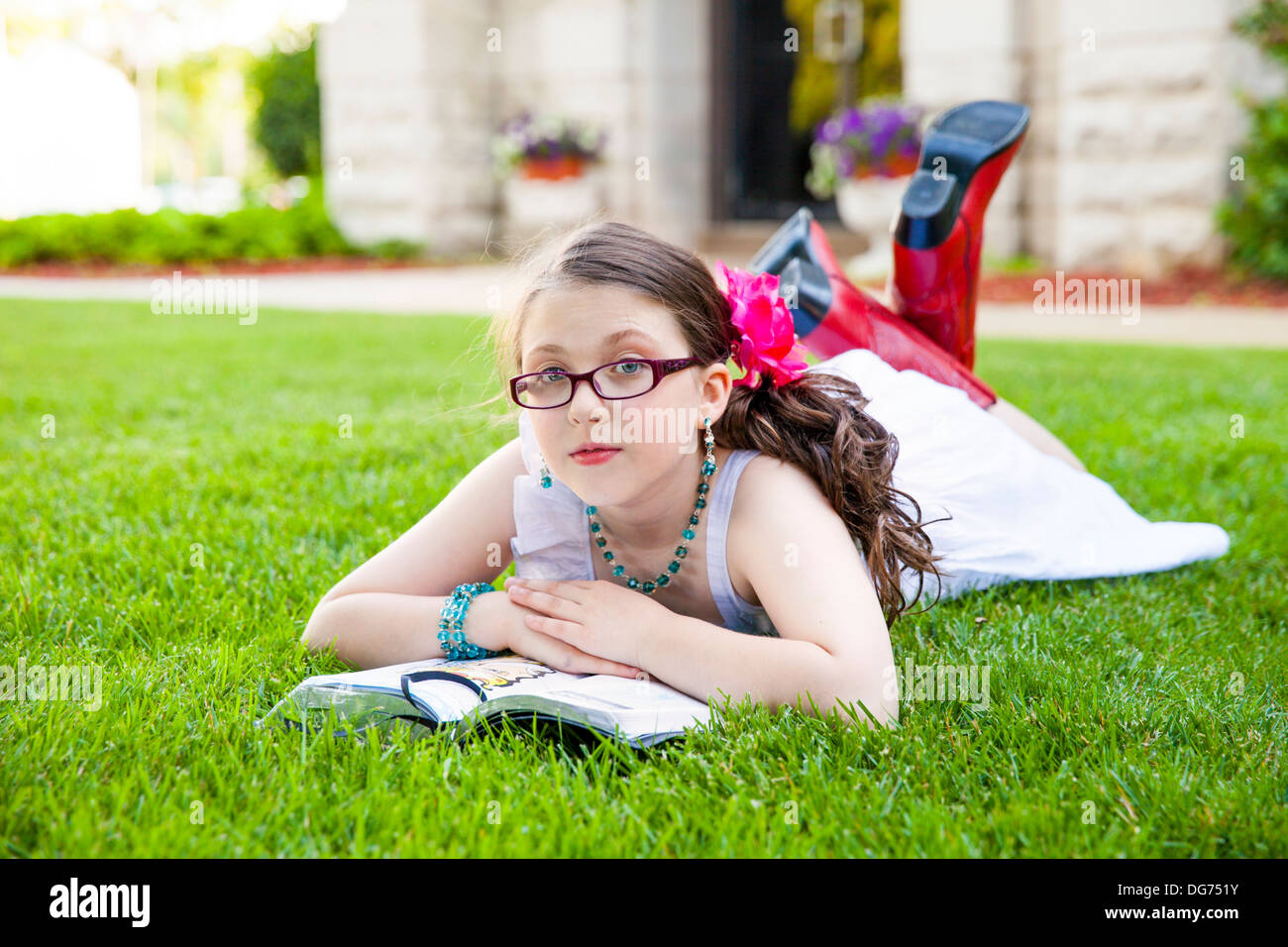 Beautiful young hispanic girl in glasses, white dress, and red boots, reads  her book outside on the grass Stock Photo - Alamy