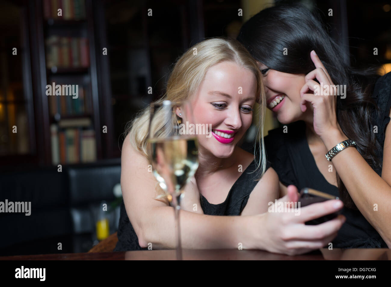 Two women on a night out using mobile phones Stock Photo