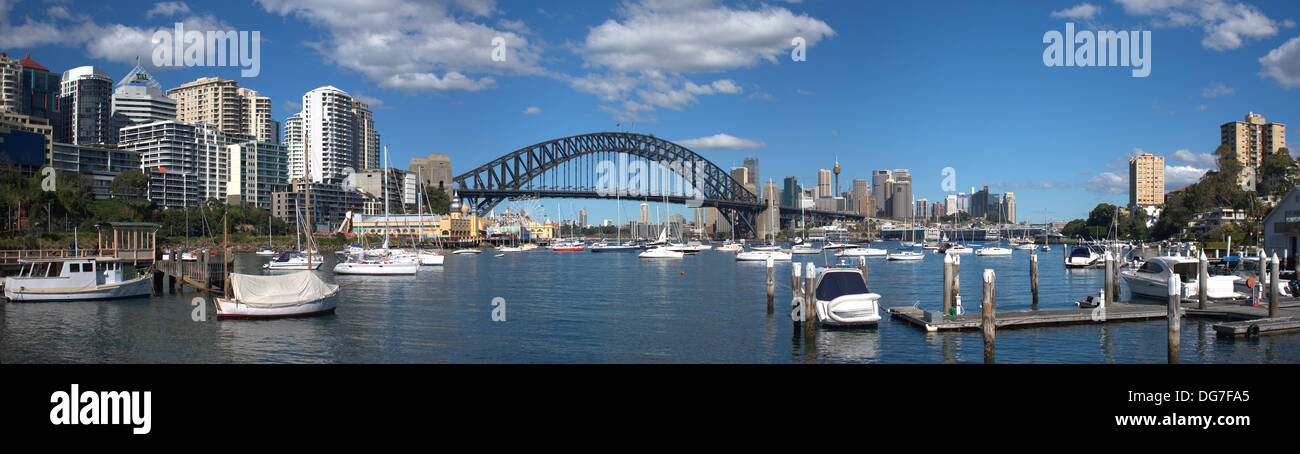 Stitched Panoramic view of Lavender Bay in Sydney on sunny day with blues skies and puffy white clouds. Stock Photo