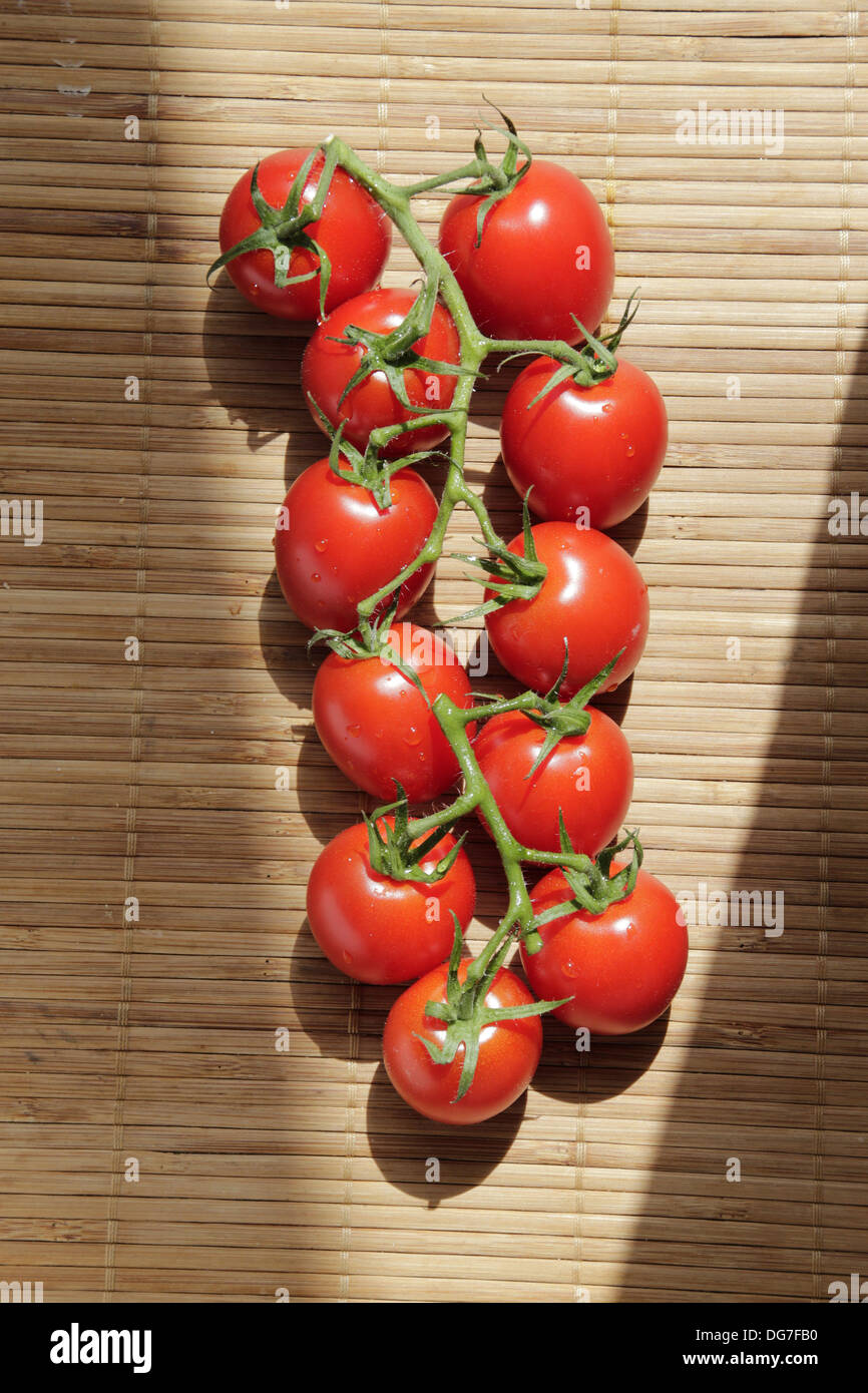 Cherry tomatoes on a stem on table with key lighting Stock Photo