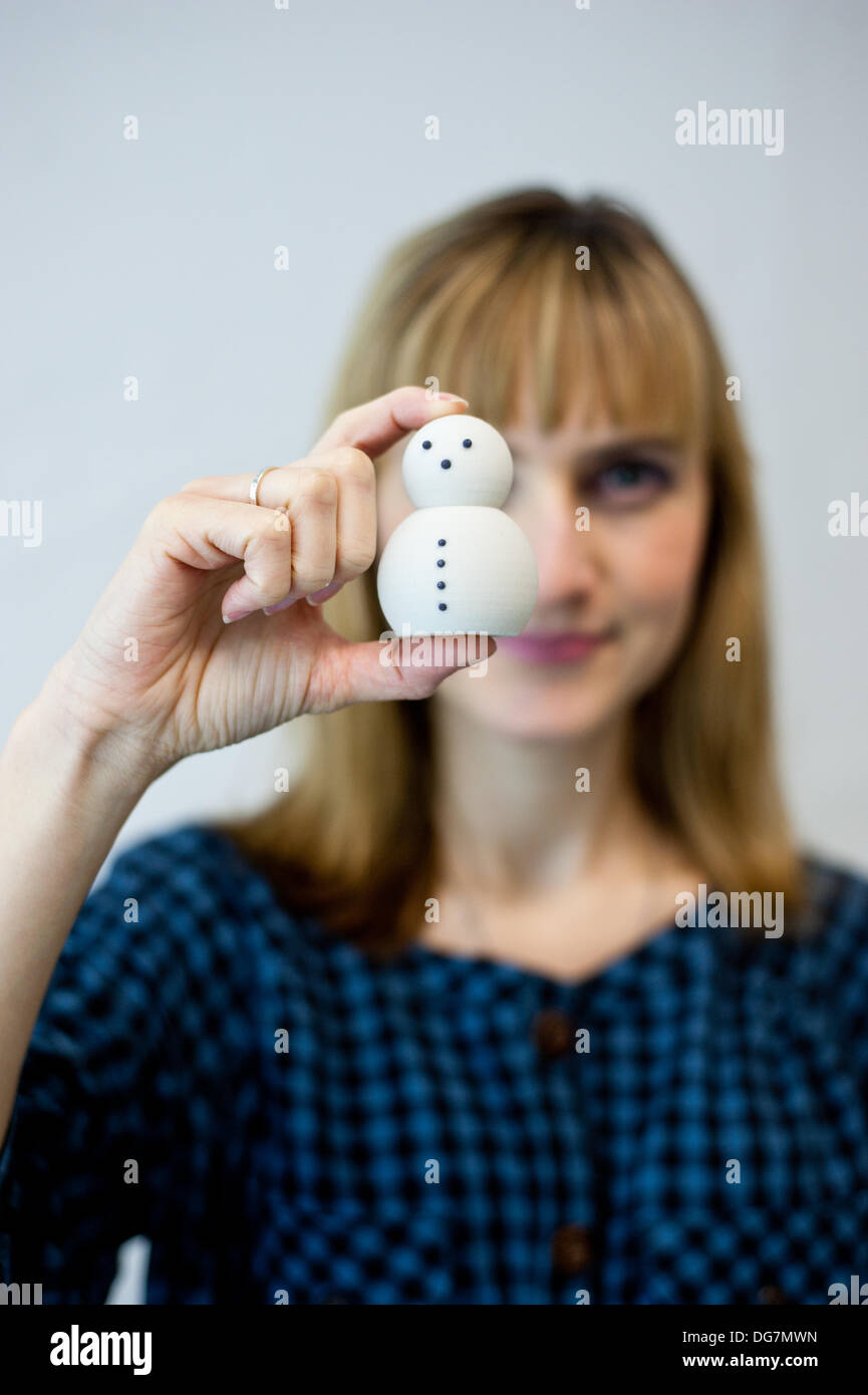 London, UK – 10 October 2013: Kathy Boyce holds on small 3D printed snowman made of plaster based composite at the Inition, Everything in 3D demo studio in Shoreditch, East London. Stock Photo