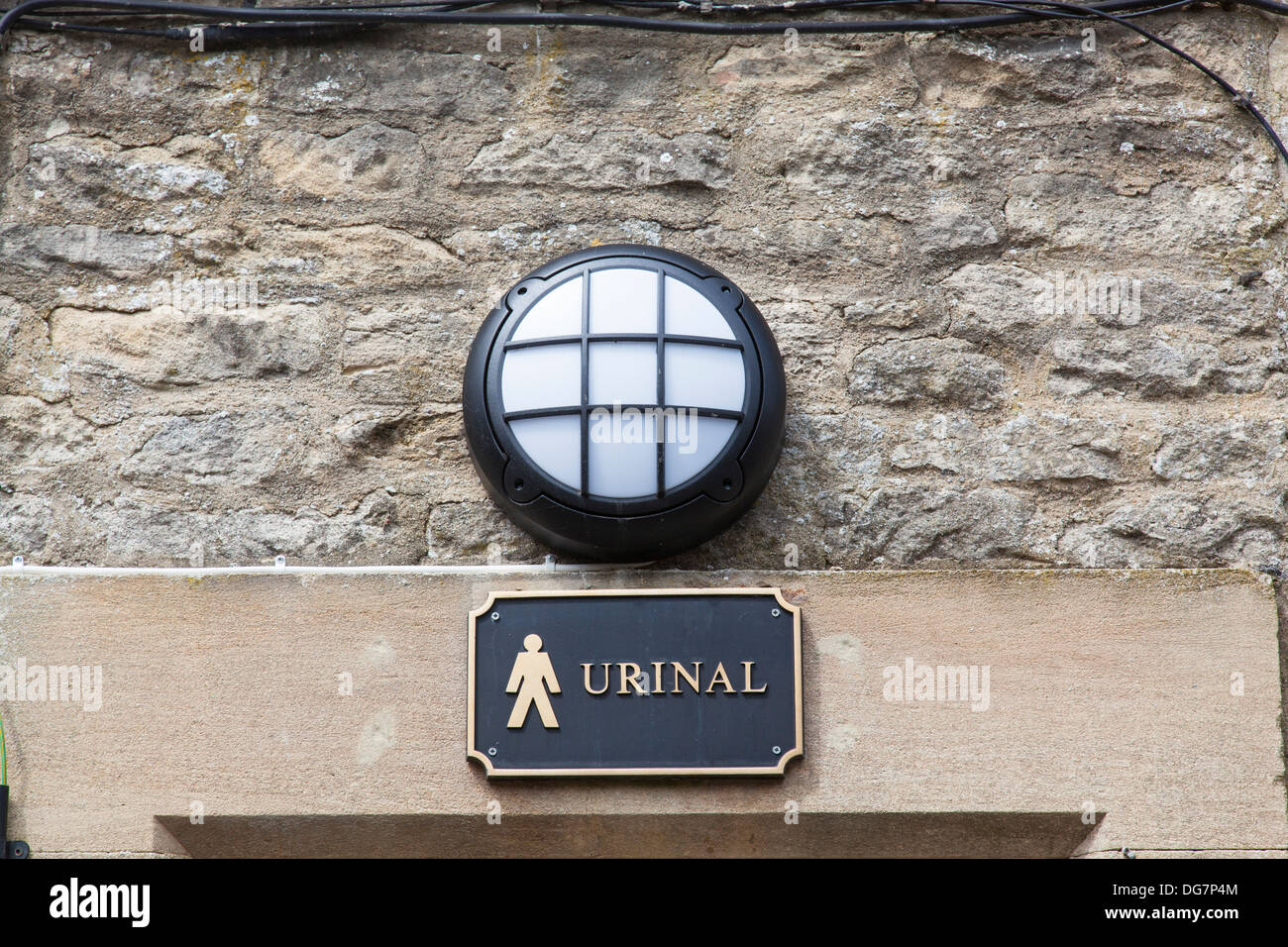 Metal sign with pictograph and text advertising the location of a men's public lavatory. Stock Photo