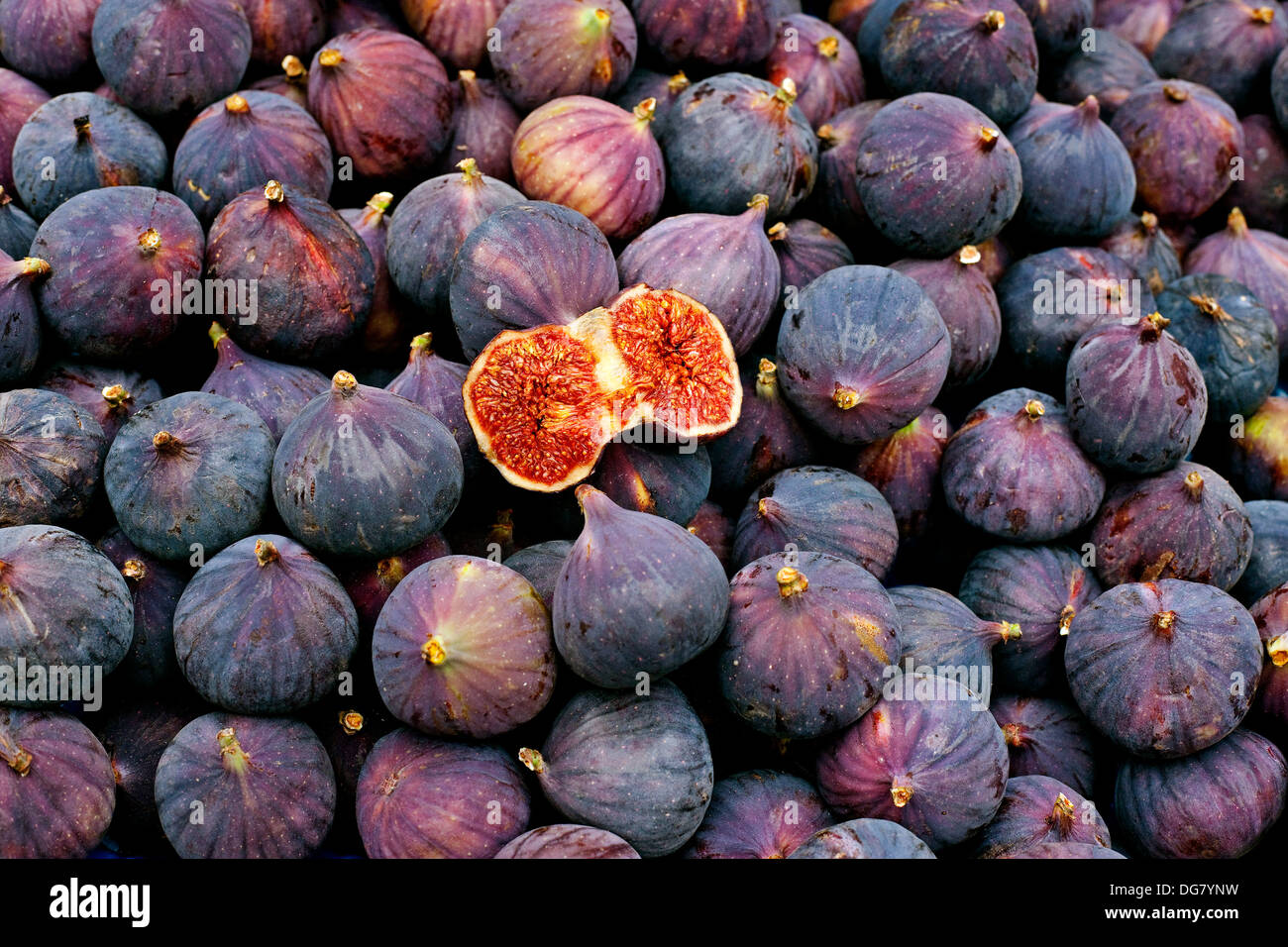 Fresh fig cut open showing the flesh and seeds inside on bed of