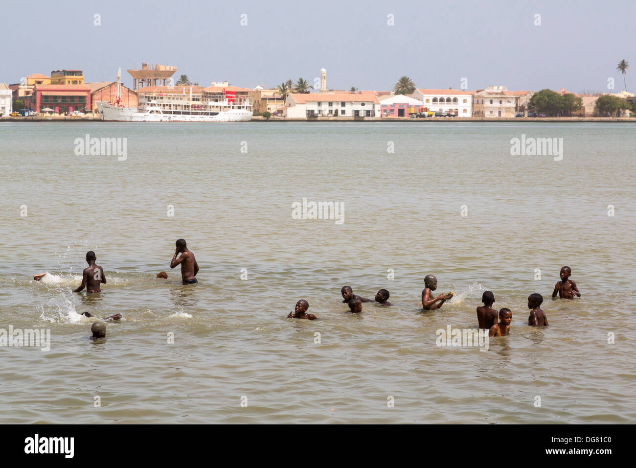 Senegal, Saint Louis. Senegalese Boys Swimming in the River Senegal, Saint Louis River Front in Background. Stock Photo