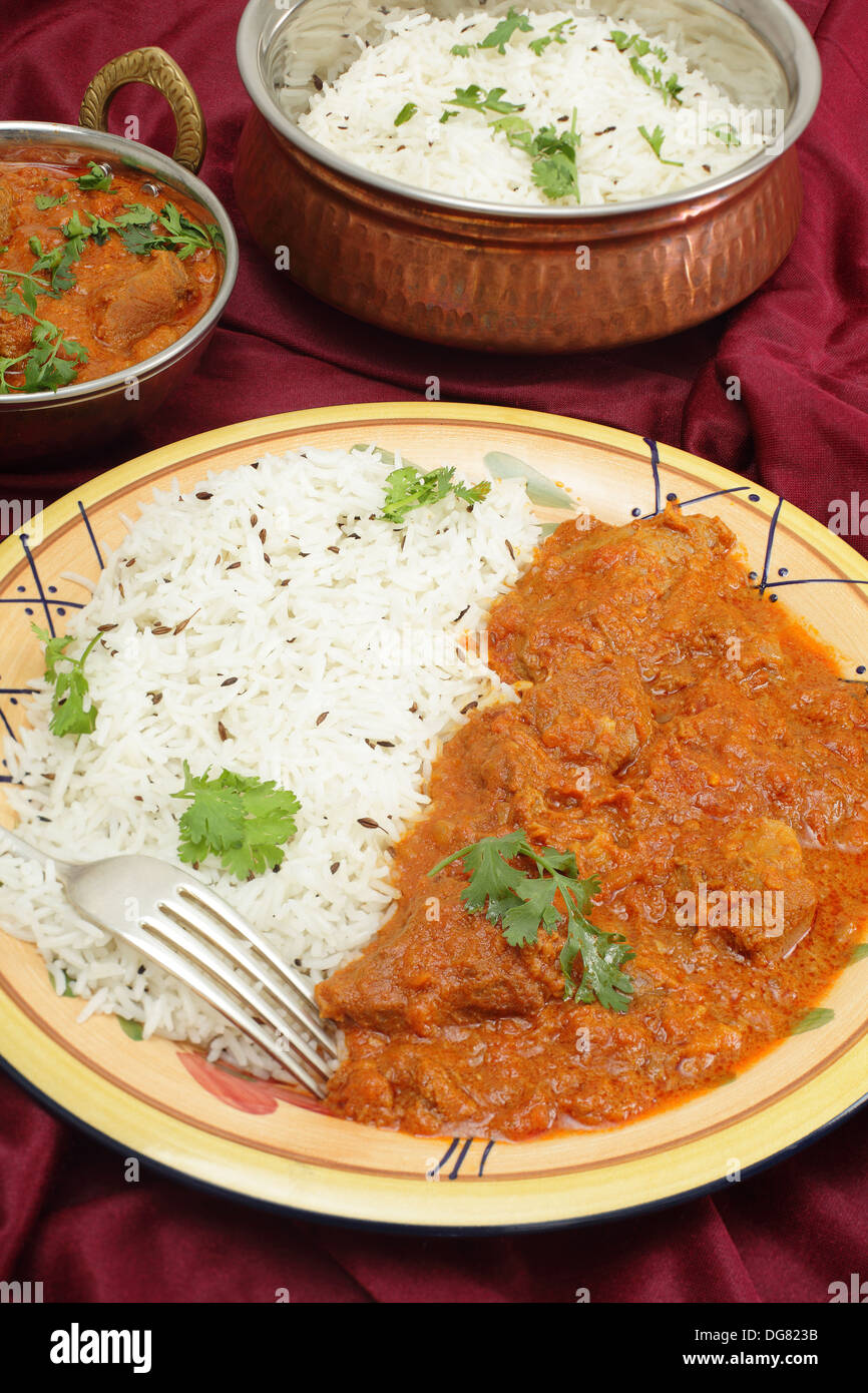Lamb rogan josh, served with jeera (cumin) rice in beaten copper bowls Stock Photo Alamy