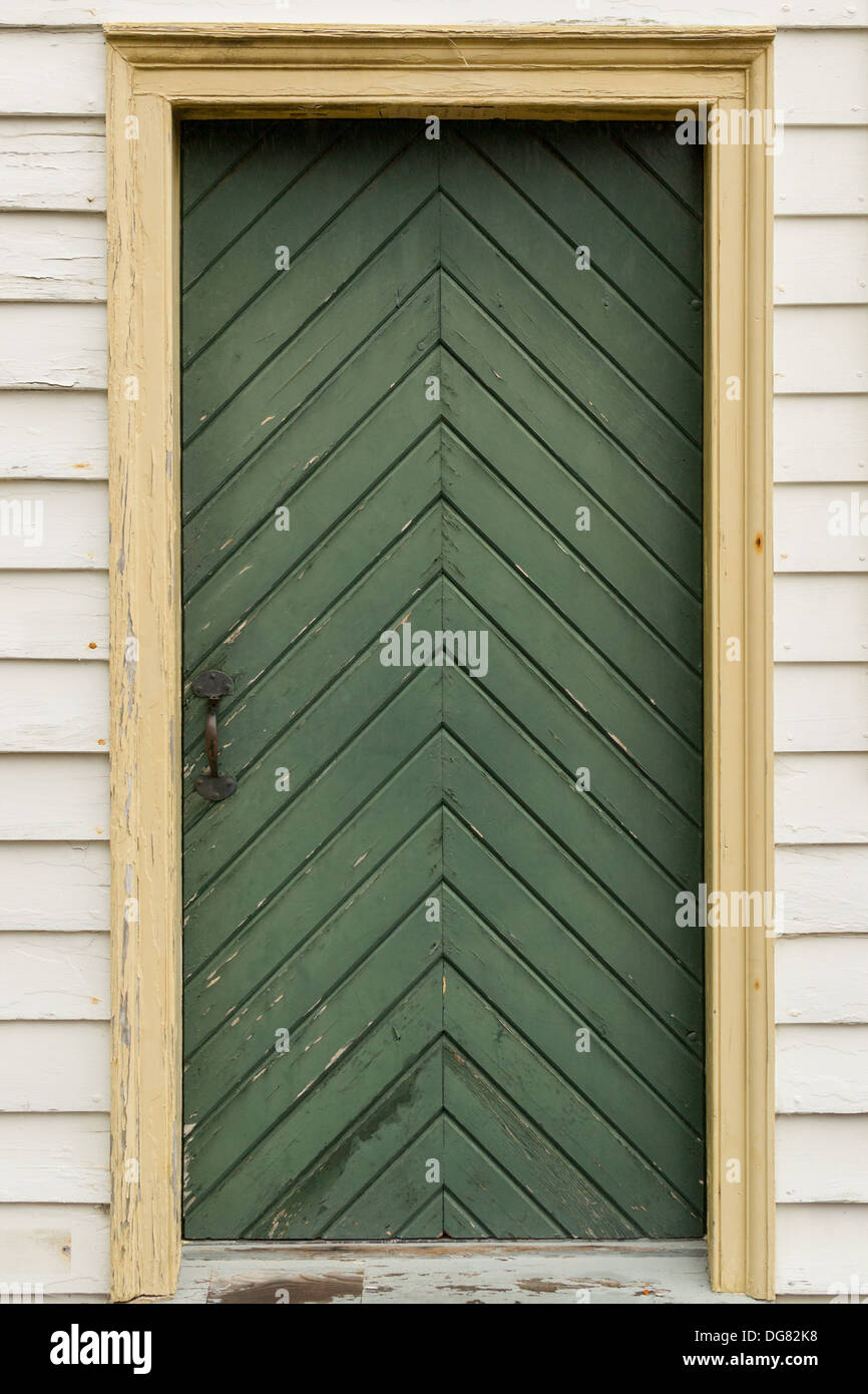 Old chevron patterned wood door set in white wood siding wall Stock Photo -  Alamy